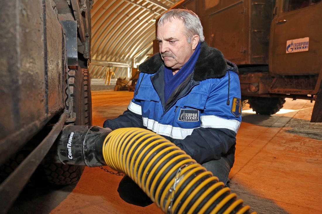 Водитель грузового КАМАЗа Юрий Астахов надевает на выхлопную трубу «рукав» вытяжной вентиляции