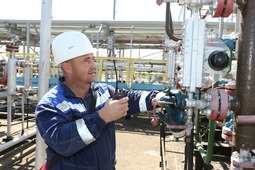 Оператор по добыче нефти и газа Дмитрий Филимонов осуществляет проверку уровня водометанольной смеси и конденсата в сепараторе